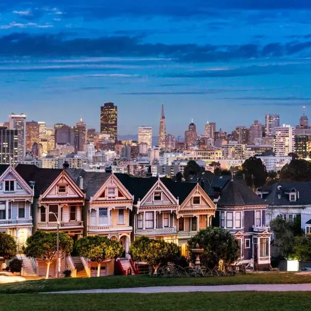 The famous 涂女士 of Alamo Square are pictured before the San Francisco skyline at twilight.